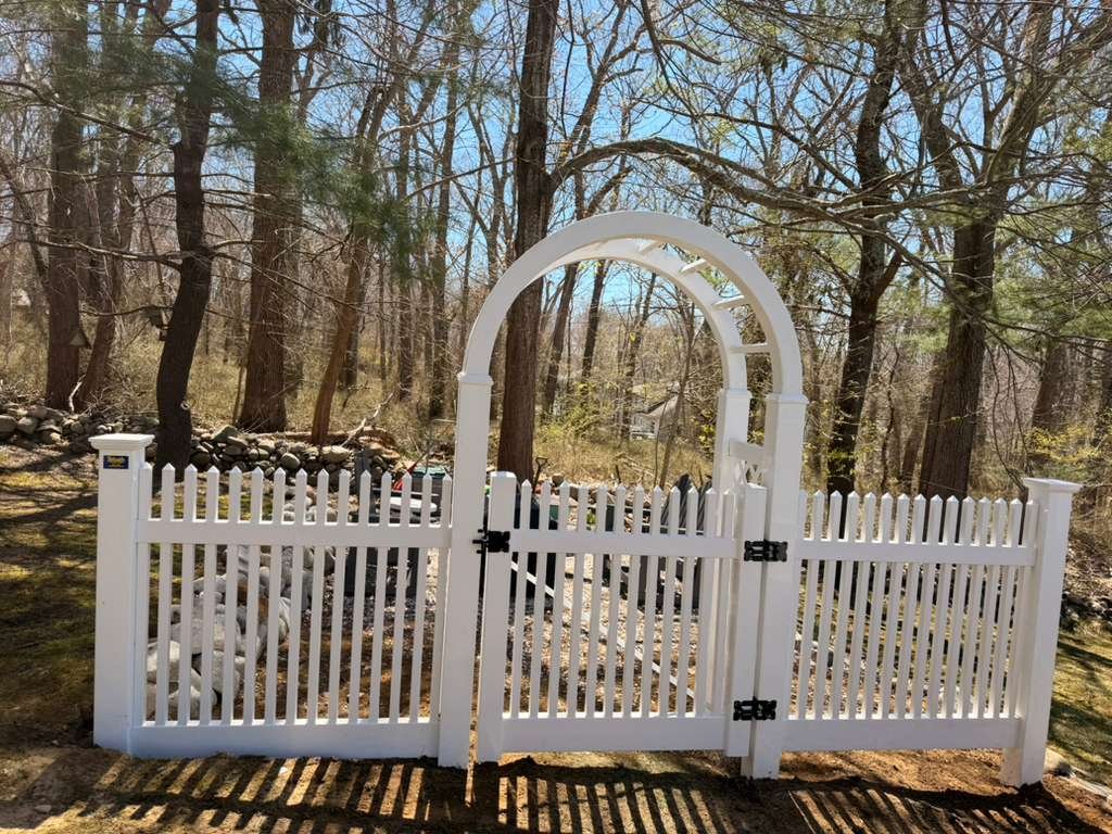 White vinyl picket fence with arched arbor gate